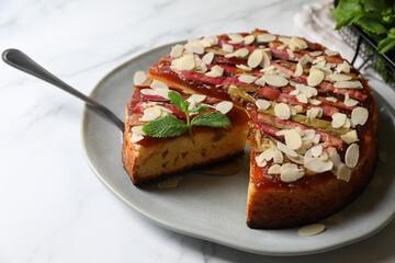 Freshly baked rhubarb pie with almond flakes and cake server on white marble table, closeup