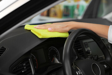 Woman cleaning car interior with rag, closeup