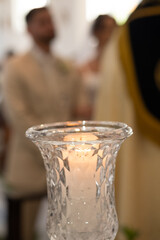 candlestick with lit candle, wedding ceremony, crystal candlestick, candlestick with bride and groom in the background, blurred background