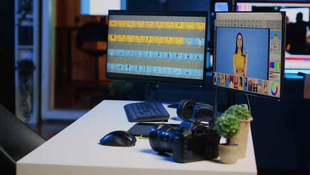 Creative agency studio desk with photo processing software interface on computer screens, graphic tablet and professional camera, panning shot. Image editing program displayed on PC monitors, close up