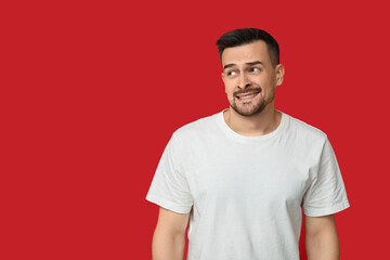 Handsome ashamed young man on red background