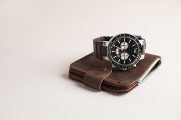 Stylish leather wallet and wristwatch on light background. Space for text
