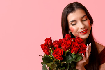 Beautiful young woman with kiss marks on her face and bouquet of roses on pink background