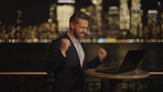 Businessman using laptop at night with neon street lights in New York City. Businessman in night Ney York. Business man using tablet laptop outdoor. Business success in night city.