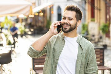 Portrait of man tourist having remote conversation communicate speaking by smartphone with friend, talking on phone unexpected good news gossip walking in urban city street. Town lifestyles outdoors