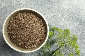 Bowl of dry seeds and fresh dill on grey table, flat lay. Space for text