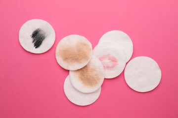 Clean and dirty cotton pads after removing makeup on pink background, flat lay © New Africa