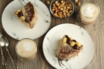 Pieces of delicious Kyiv Cake served with coffee on wooden table, flat lay