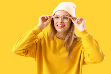 Young woman in eyeglasses on yellow background