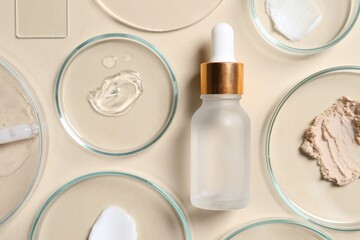 Fototapeta na wymiar Bottle of cosmetic serum and petri dishes with samples on beige background, flat lay