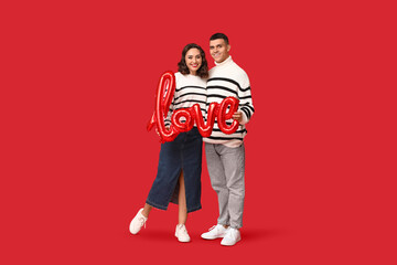 Loving young couple with balloon in shape of word LOVE on red background. Celebration of Saint...