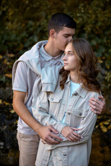 Fototapeta premium Young Cute Female Hugs Boyfriend. In Autumn Outdoor. Lovers Walking in Park. Attractive Funny Couple. Lovestory in Forest. Man and Woman. Cute Lovers in the Park. Family Concept. Happy Couple.