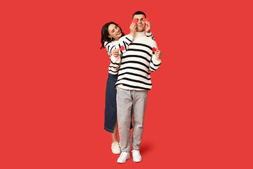 Loving young couple with paper hearts on red background. Celebration of Saint Valentine's Day