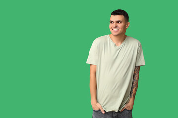 Handsome ashamed young man on green background