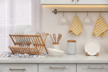 Drying rack with clean dishes on countertop in kitchen