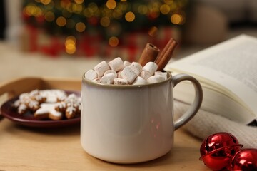 Christmas cocoa with marshmallows and cinnamon sticks in grey cup on wooden tray indoors, closeup