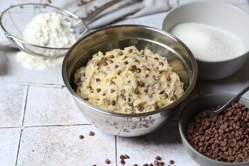 Chocolate chip cookie dough in bowl and ingredients on table
