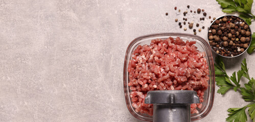 Obraz na płótnie Canvas Manual meat grinder, beef mince, peppercorns and parsley on light grey table, flat lay. Banner design with space for text