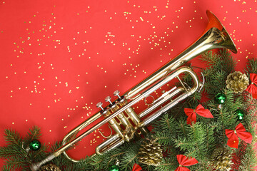 Composition with trumpet, fir branches and Christmas decorations on red background