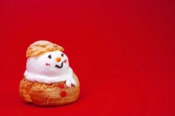 Snowman Choux Cream isolated on red background. Choux pastry snowman, Ideas for Christmas food, DIY, Do It Yourself. Greeting card for Christmas and New year, copy space for Text
