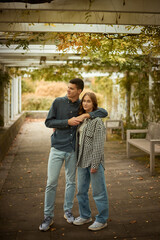 Fototapeta premium Young Cute Female Hugs Boyfriend. In Autumn Outdoor. Lovers Walking in Park. Attractive Funny Couple. Lovestory in Forest. Man and Woman. Cute Lovers in the Park. Family Concept. Happy Couple.