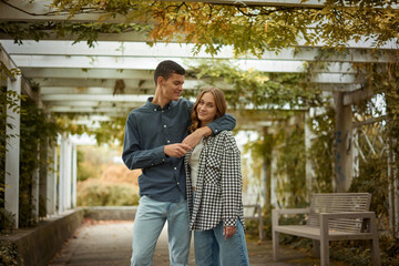 Young Cute Female Hugs Boyfriend. In Autumn Outdoor. Lovers Walking in Park. Attractive Funny Couple. Lovestory in Forest. Man and Woman. Cute Lovers in the Park. Family Concept. Happy Couple.