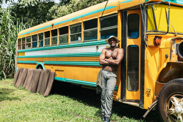 Man leaning on a vintage school bus in reparation - obrazy, fototapety, plakaty