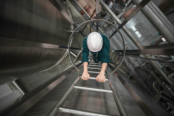The male worker up the ladder is for inspection stainless steel tank chemical. © chitsanupong