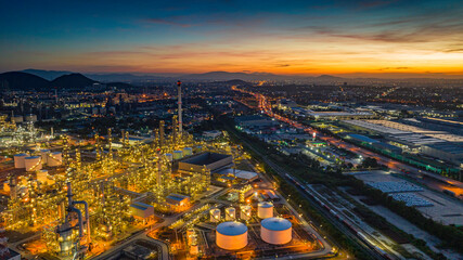 Obraz premium Aerial view of the morning of the oil refinery from the drone of the tower of the Petrochemistry industry in the oil​ and​ gas​ ​industry with​ cloud​ sun orange​