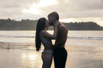 Couple kissing on the beach at sunset