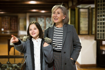 Cute interested preteen girl visiting museum of applied arts with grandmother, exploring ancient artworks ..