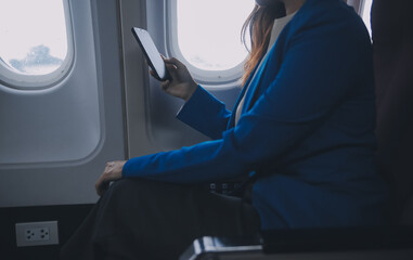 Young Asian business woman talking on smartphone, businesswoman working while flying at plane,...