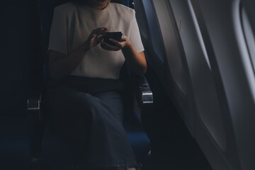Attractive Asian female passenger of airplane sitting in comfortable seat while working laptop and tablet with mock up area using wireless connection. Travel in style, work with grace.