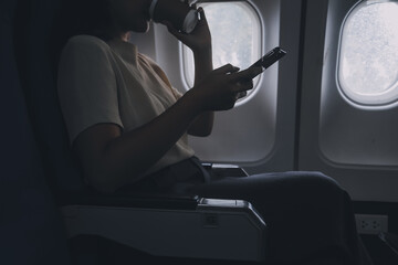 Asian woman enjoying enjoys a coffee comfortable flight while sitting in the airplane cabin, Passengers near the window.