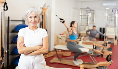 Fototapeta na wymiar Elderly athletic woman in sportswear posing in pilates studio..