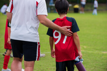 Male youth football coach giving some advices and encouraging his team player in a school...