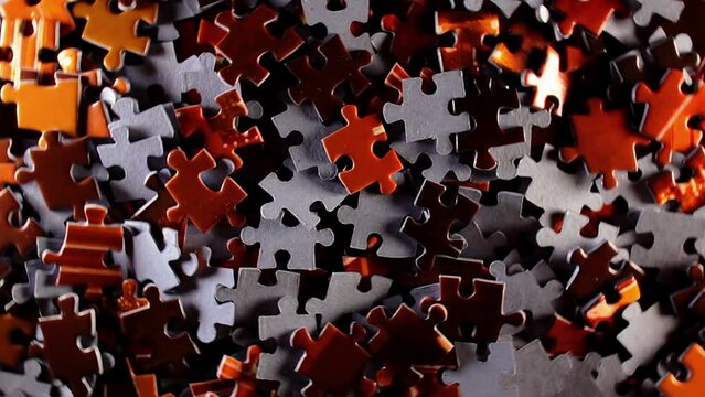 Background of Colored Puzzle Pieces that Rotating Counterclockwise - Top View. Texture of Incomplete Red and Grey Jigsaw Puzzle with Low Key Light - Left Rotation