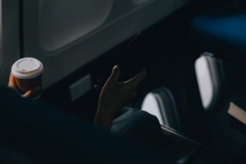 Asian woman enjoying enjoys a coffee comfortable flight while sitting in the airplane cabin, Passengers near the window.