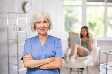 Fototapeta na wymiar Smiling female cosmetologist consulting young patient at bright aesthetic clinic room