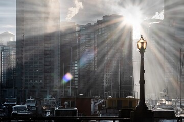 Sunbeams over the modern city and harbour with boats and a city light. Coal Harbour. Vancouver downtown. BC. Canada