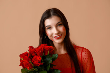 Happy young woman with kiss marks on her face and bouquet of roses on brown background