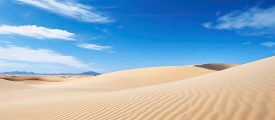 Fototapeta na wymiar Sand dunes under a blue sky at Park Natural Corralejo, Fuerteventura, Spain.