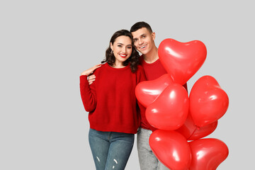 Fototapeta na wymiar Loving young couple with heart-shaped balloons on grey background. Celebration of Saint Valentine's Day