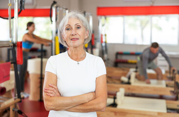 Elderly athletic woman in sportswear posing in pilates studio..