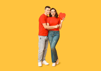 Loving young couple with gift box on yellow background. Celebration of Saint Valentine's Day