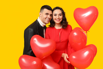 Fototapeta na wymiar Loving young couple with heart-shaped balloons on yellow background. Celebration of Saint Valentine's Day