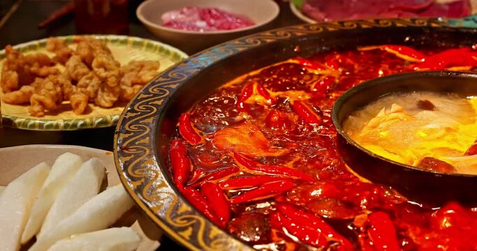 Chinese spicy hot pot cuisine. A layer of red chili pepper floats in the boiling hot pot base. Famous Chongqing Spicy Hot Pot, China.