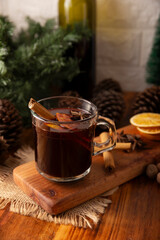 Spiced wine or Christmas mulled wine with orange, cinnamon, star anise, clove, nutmeg and other ingredients on a wooden rustic table. Traditional hot drink at winter time and Christmas holidays.
