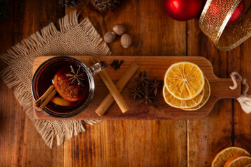 Spiced wine or Christmas mulled wine with orange, cinnamon, star anise, clove, nutmeg and other ingredients on a wooden rustic table. Traditional hot drink at winter time and Christmas holidays.