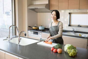 綺麗なキッチンに立つ女性　料理をする